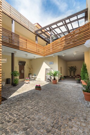 A courtyard with cobblestone flooring, wooden railings, potted plants, and a sign indicating a restaurant. - Aeterno Eco Guest House (Rome)