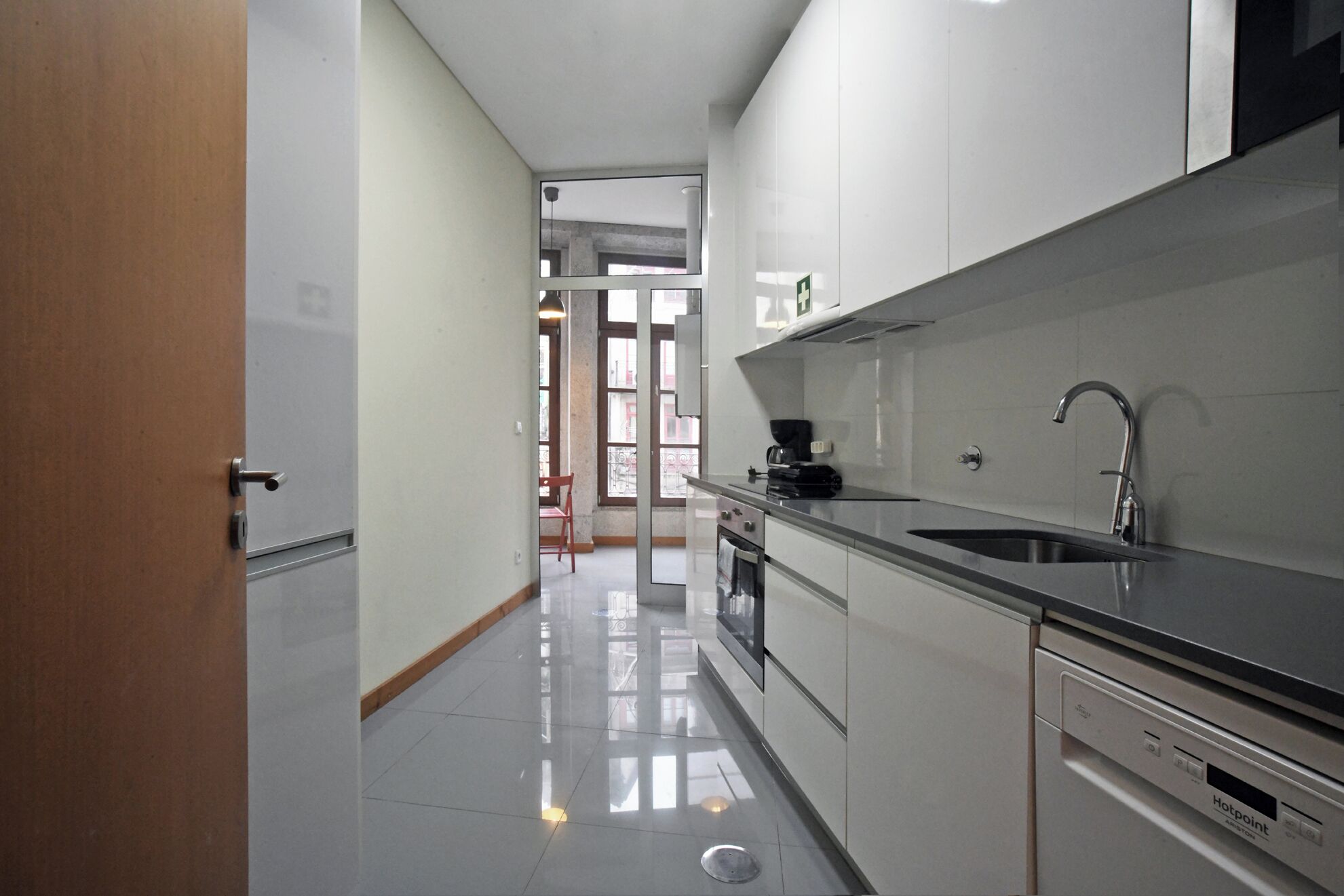 A modern kitchen with stainless steel appliances, a black countertop, and a view into the living area.
