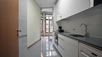 Een moderne keuken met roestvrijstalen apparatuur, een zwart aanrechtblad en uitzicht op de woonkamer.