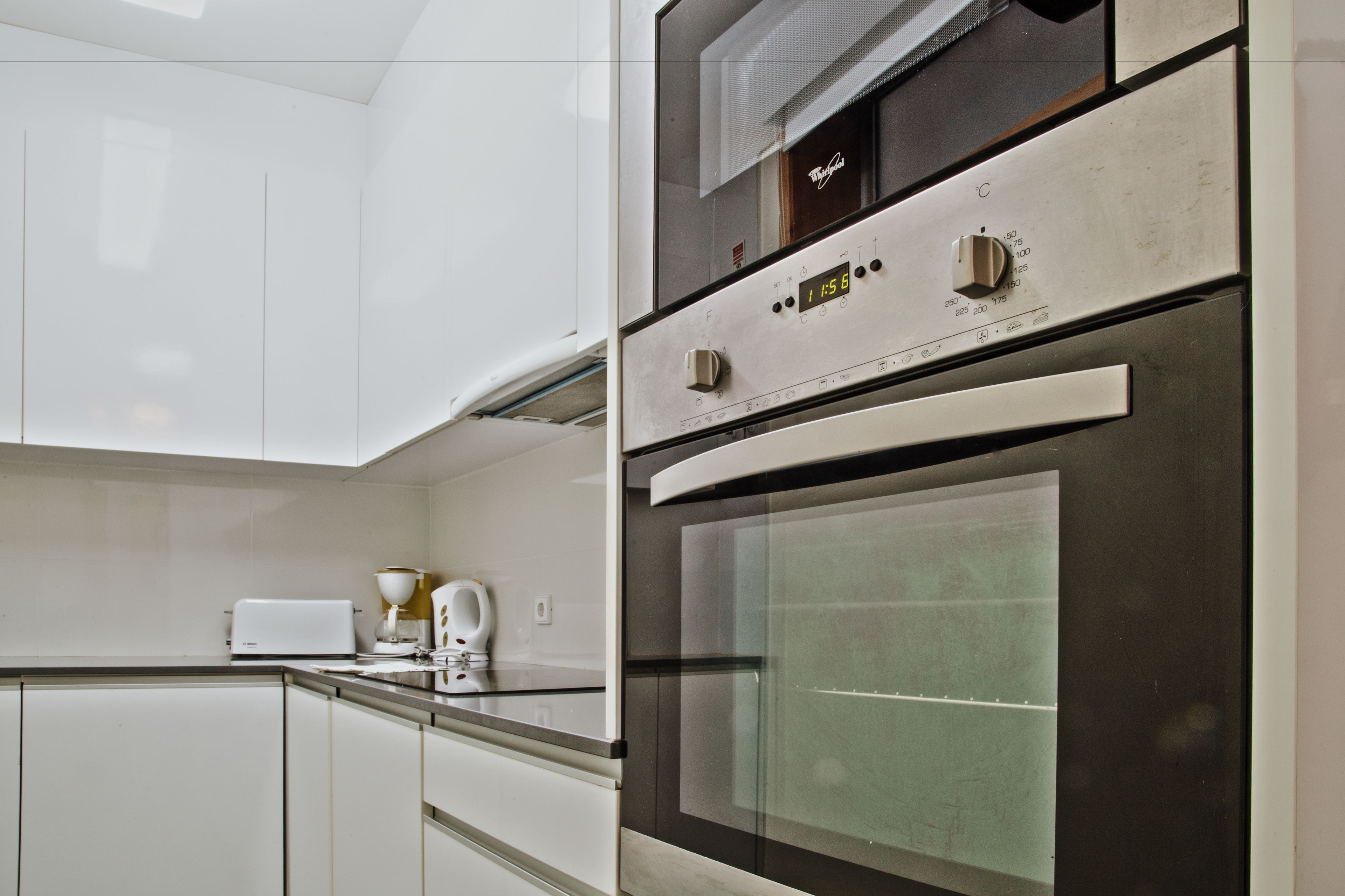 Una cocina moderna con electrodomésticos de acero inoxidable, armarios blancos y horno empotrado.