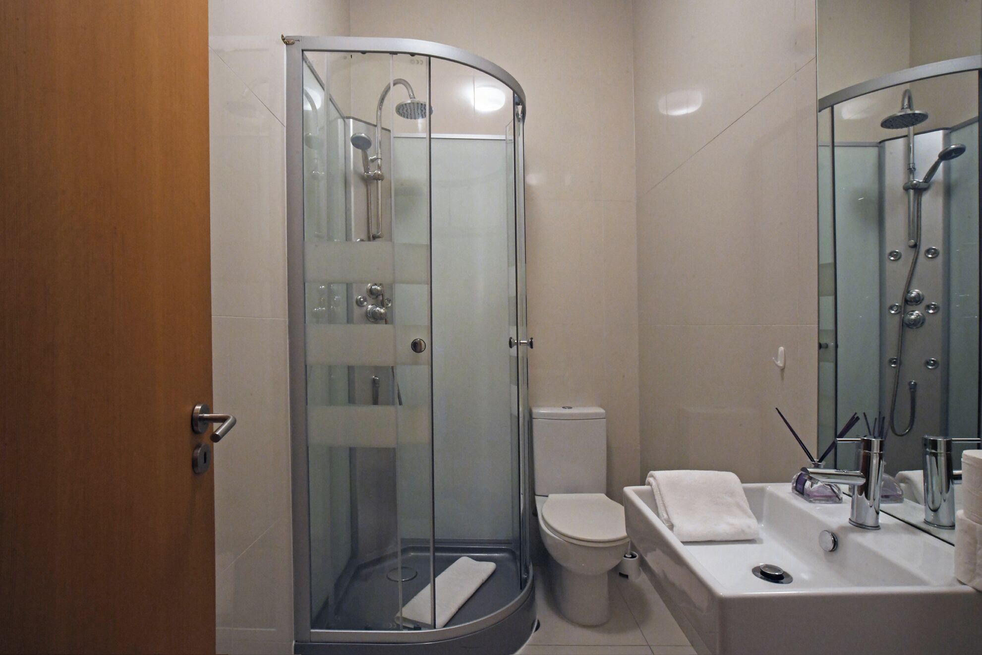 Et moderne badeværelse med en glasafskærmet brusekabine, toilet og et spejl med vask.