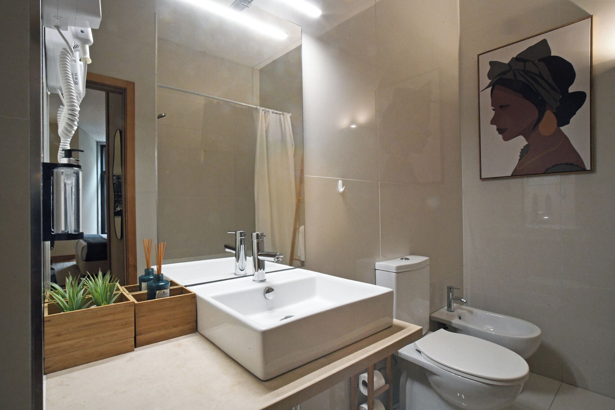 A modern bathroom with a large mirror, two sinks, a toilet, and a bidet.