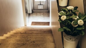 A staircase with a marble floor leading to a kitchen area. There are two white planters with flowers on the wall. - Spot Apartments (Porto)