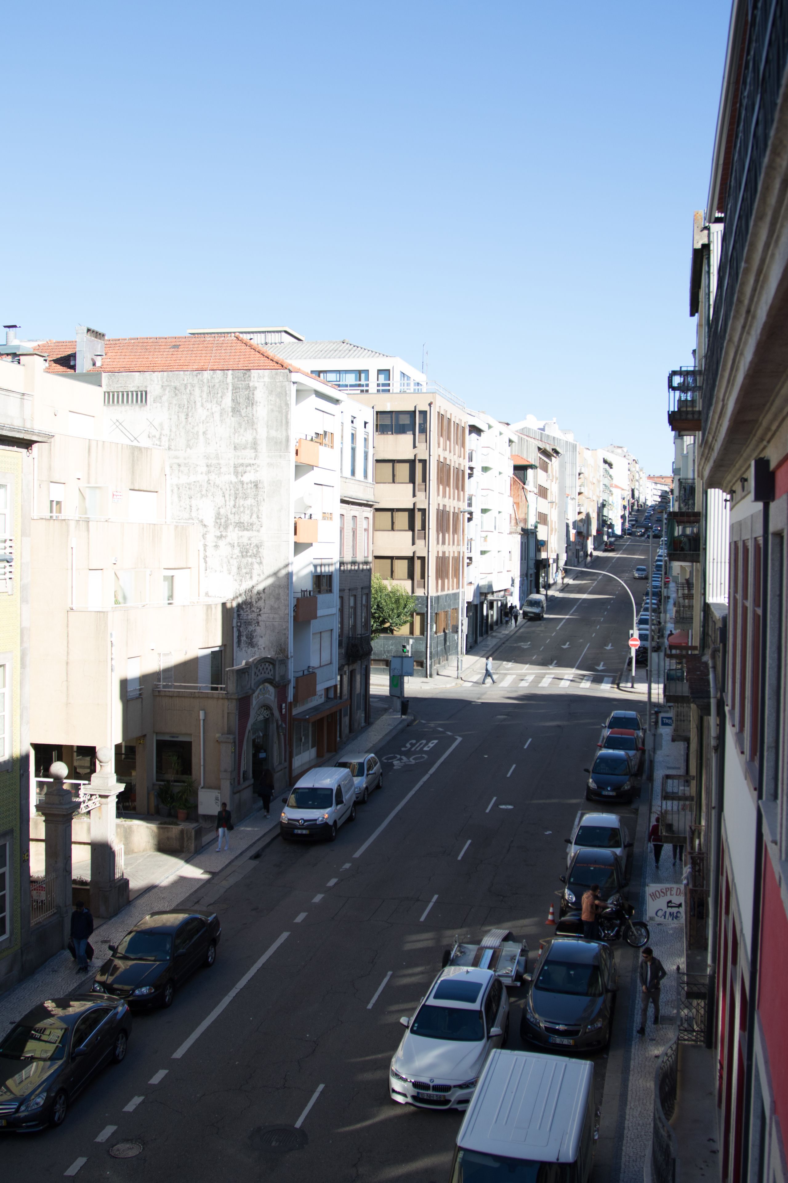 Vista de una calle con edificios, coches estacionados y cielo despejado.