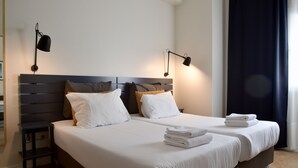 A double bed with white linens, two bedside tables, and a headboard with horizontal slats. - Spot Apartments (Porto)