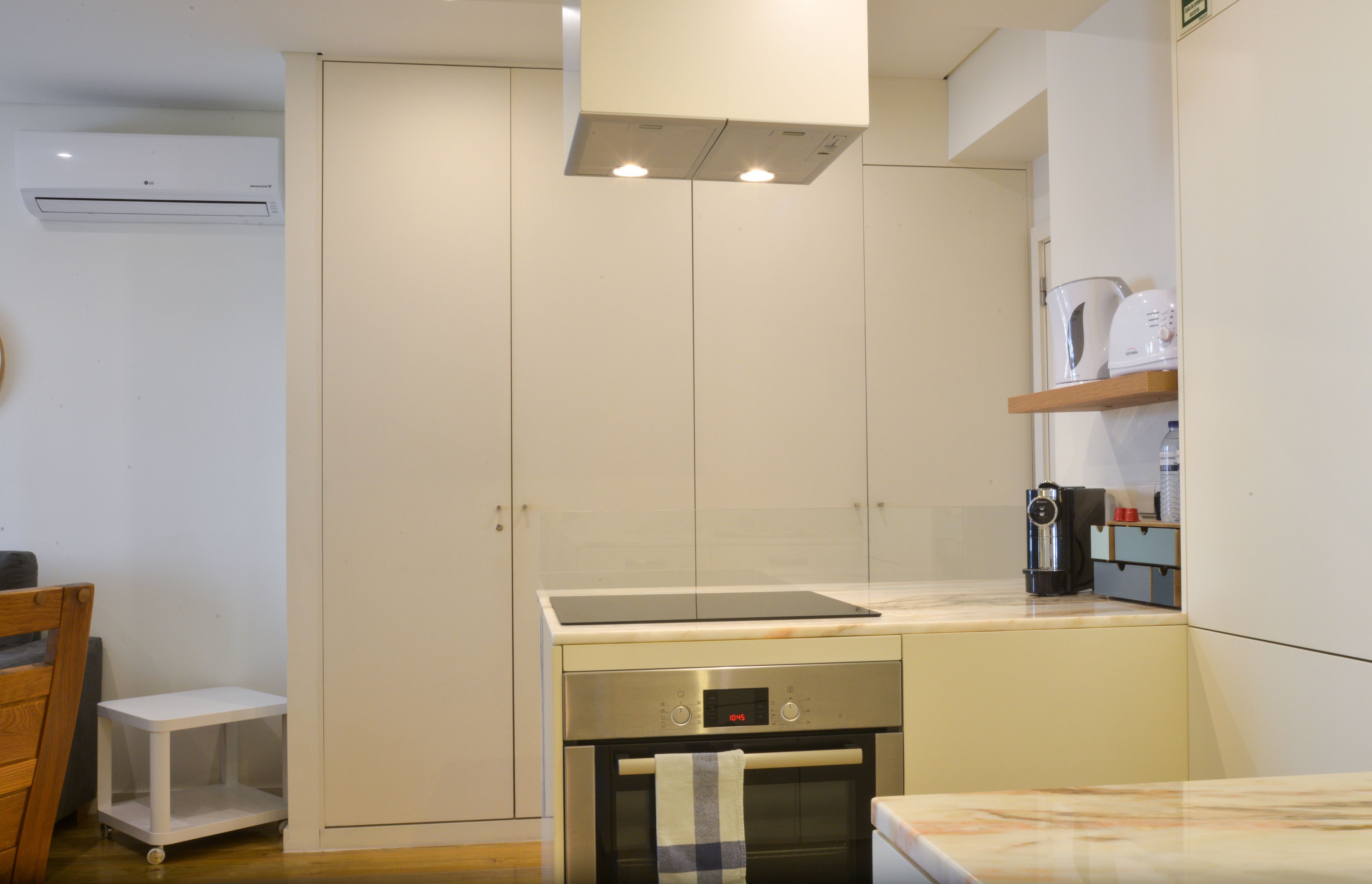 A compact kitchen with a built-in oven, a microwave, and a coffee maker on the countertop.