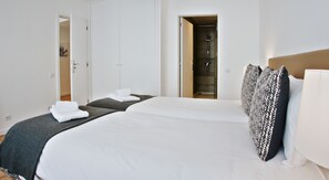 A hotel room with a large bed, a wardrobe, and a bathroom visible through an open door. - Spot Apartments Ceuta (Porto)