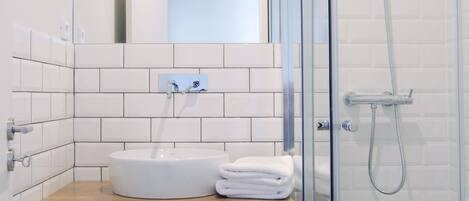 Une salle de bain moderne avec une douche à l’italienne en verre, un lavabo blanc et un meuble-vasque en bois.