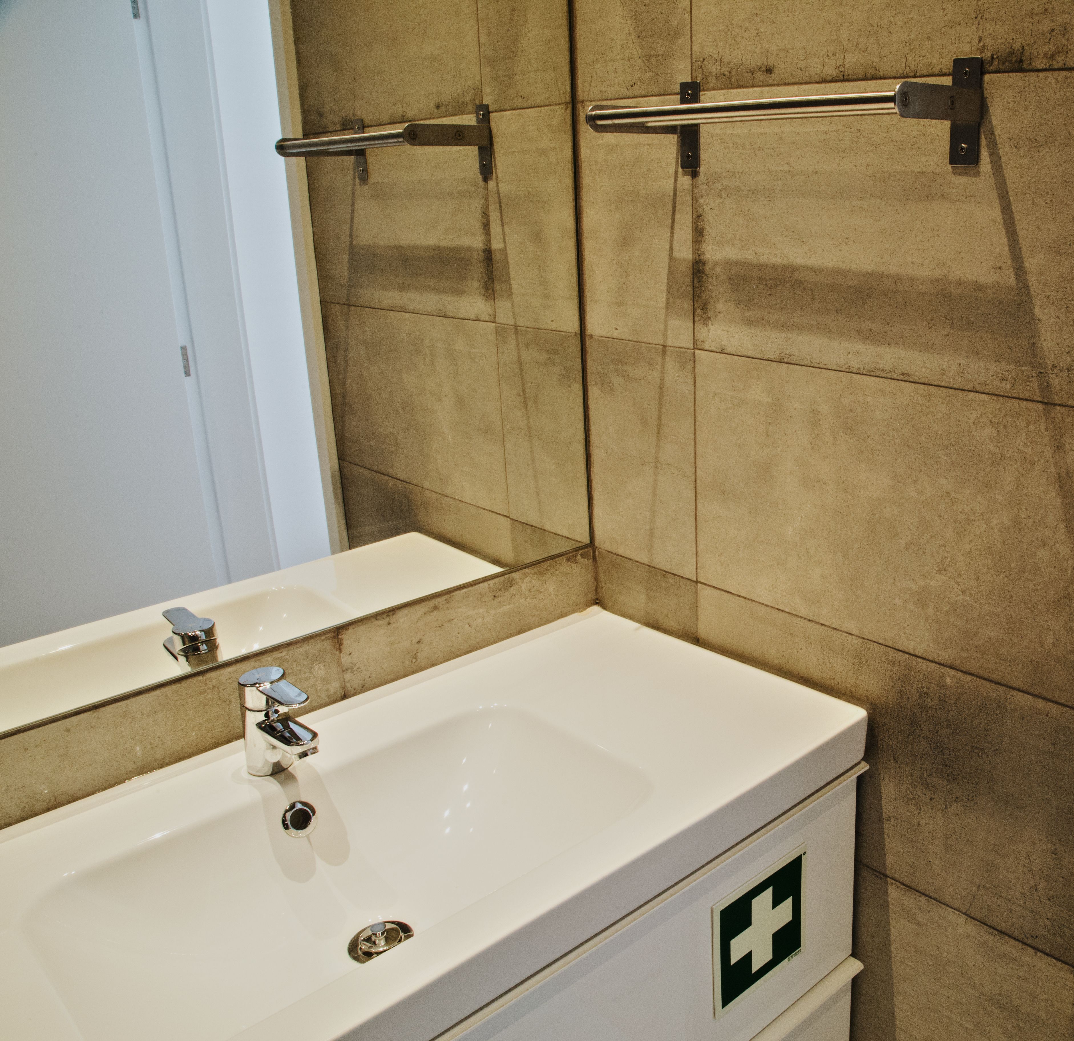 A bathroom with a white sink, a mirror, and a towel rack.