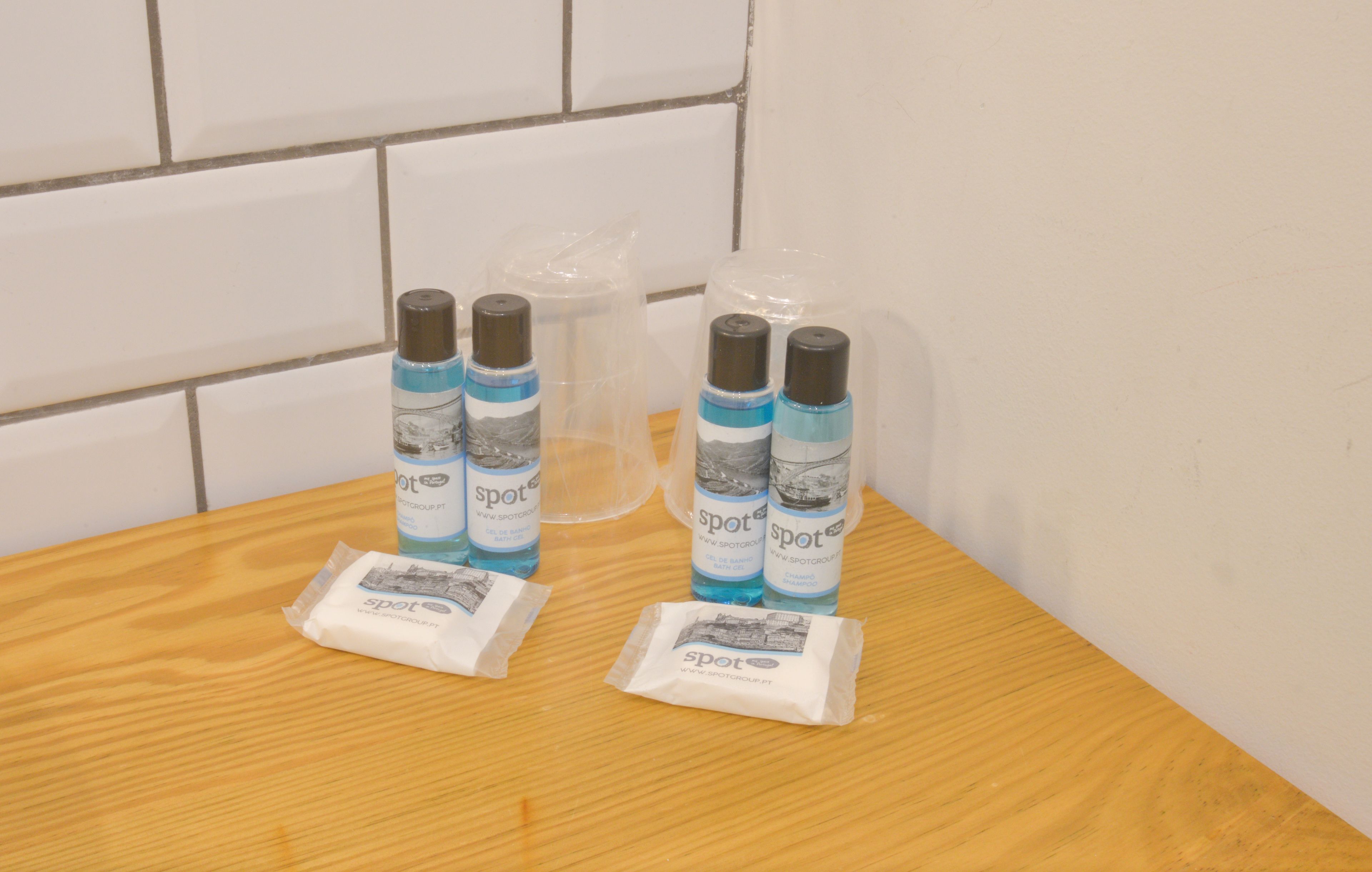 A wooden table with three bottles of 'spot' brand deodorant and two packets of the same brand on it.