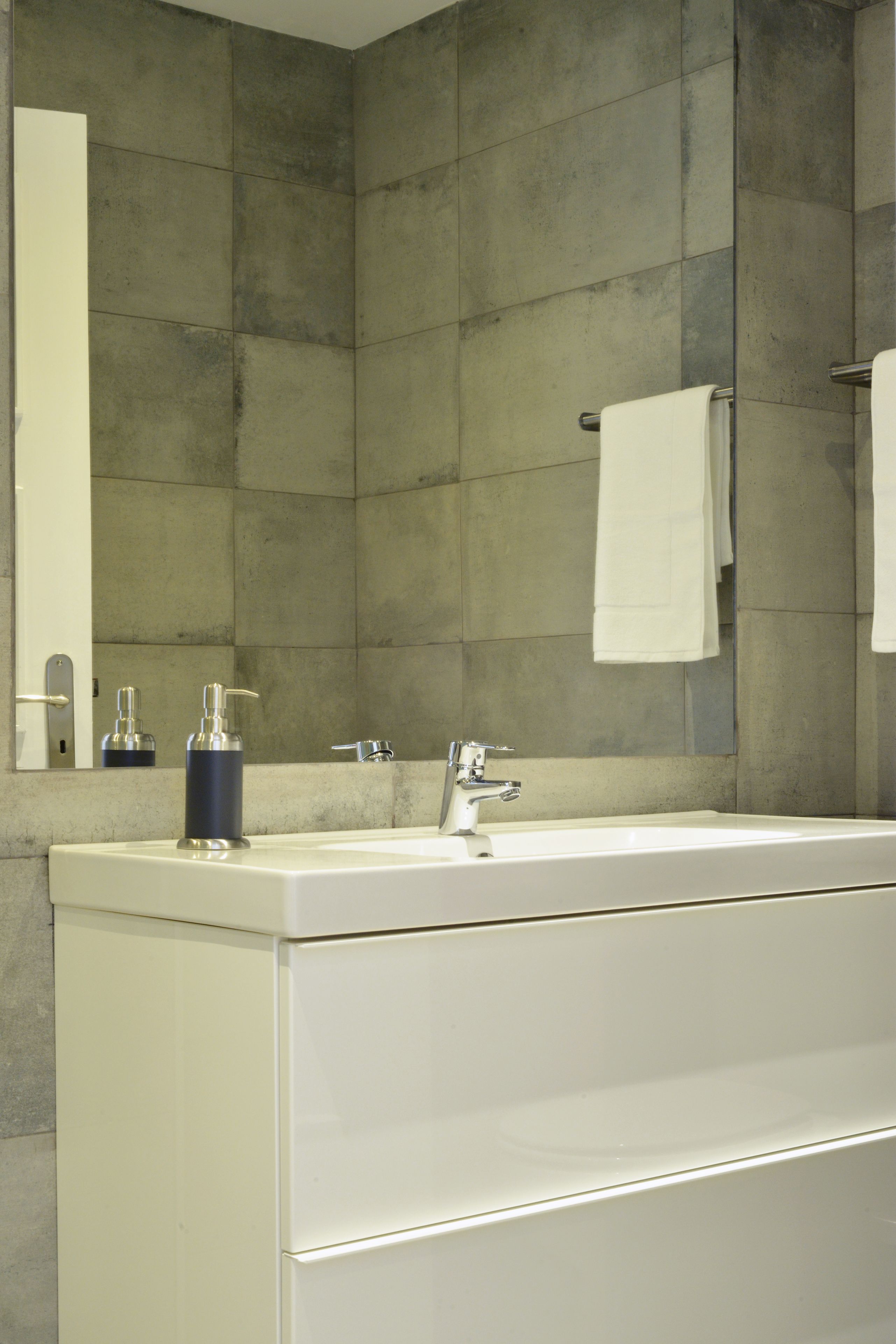A modern bathroom with a large sink, a mirror, and a towel rack.