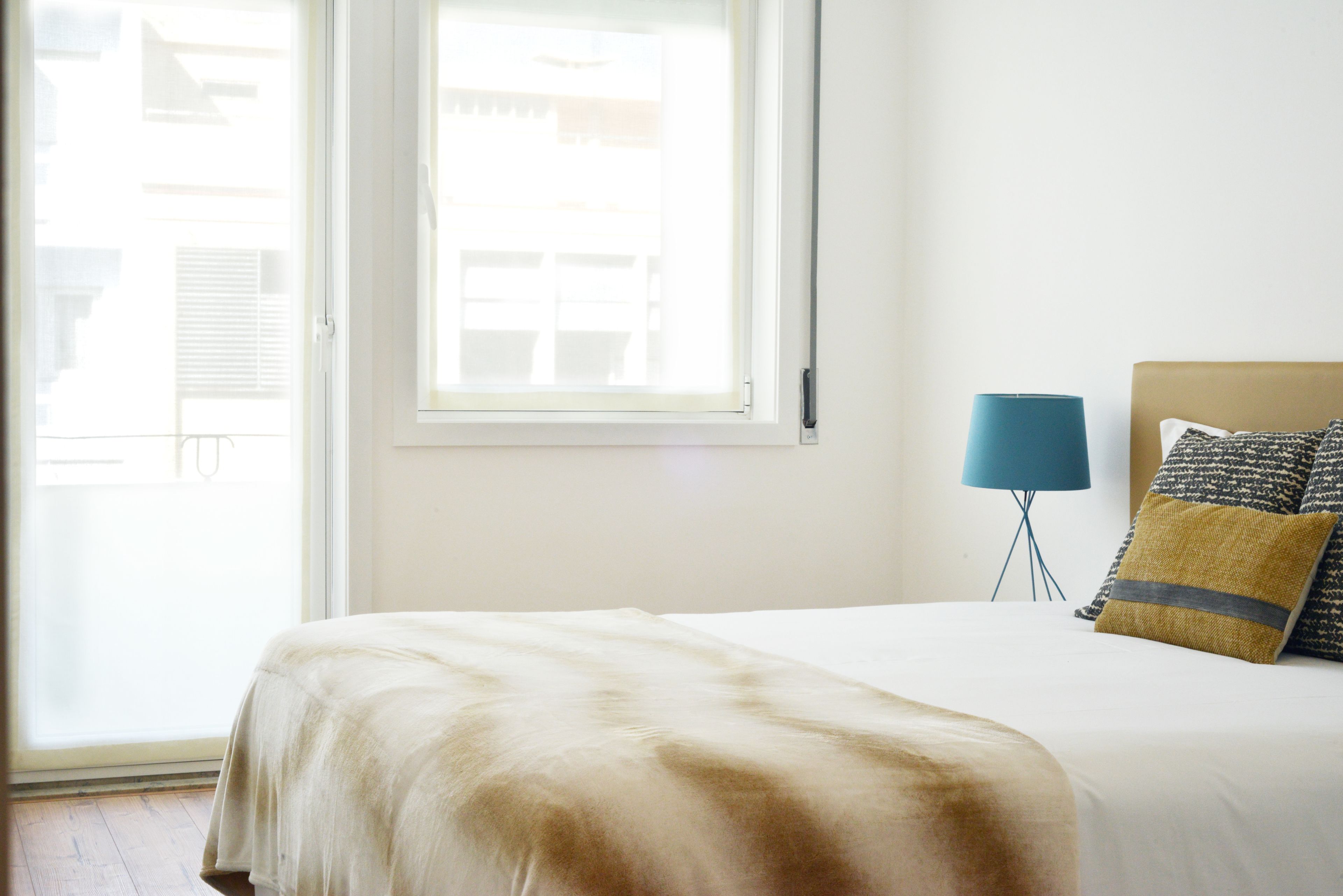 Een slaapkamer met een bed, een raam en een vloerlamp.