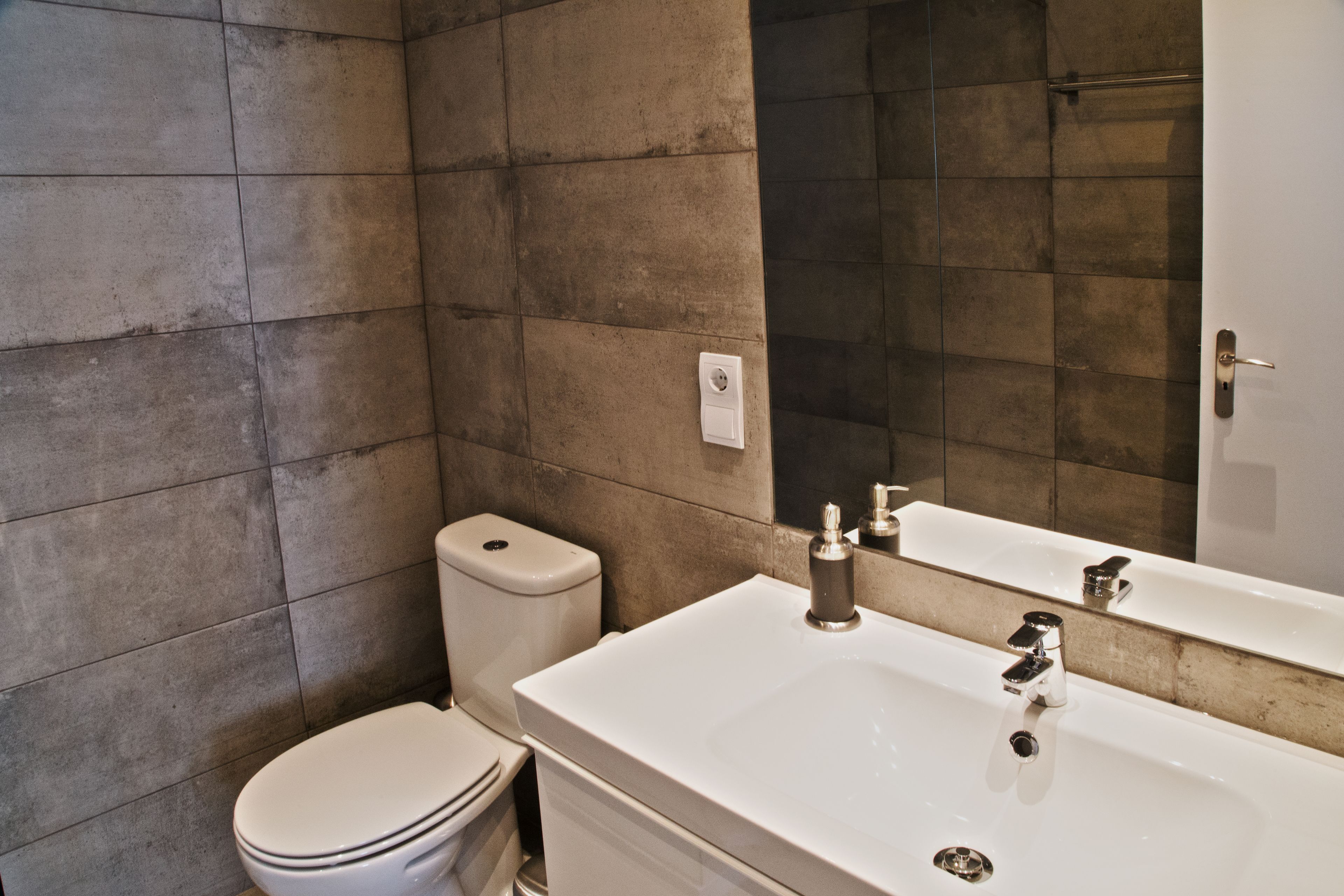 Een badkamer met een wit wastafel, een spiegel en een toilet.