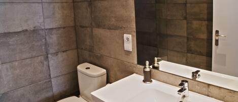 A bathroom with a white sink, a mirror, and a toilet.
