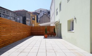 A courtyard with a wooden fence, tiled floor, and a small table with chairs. - Spot Apartments Ceuta (Porto)