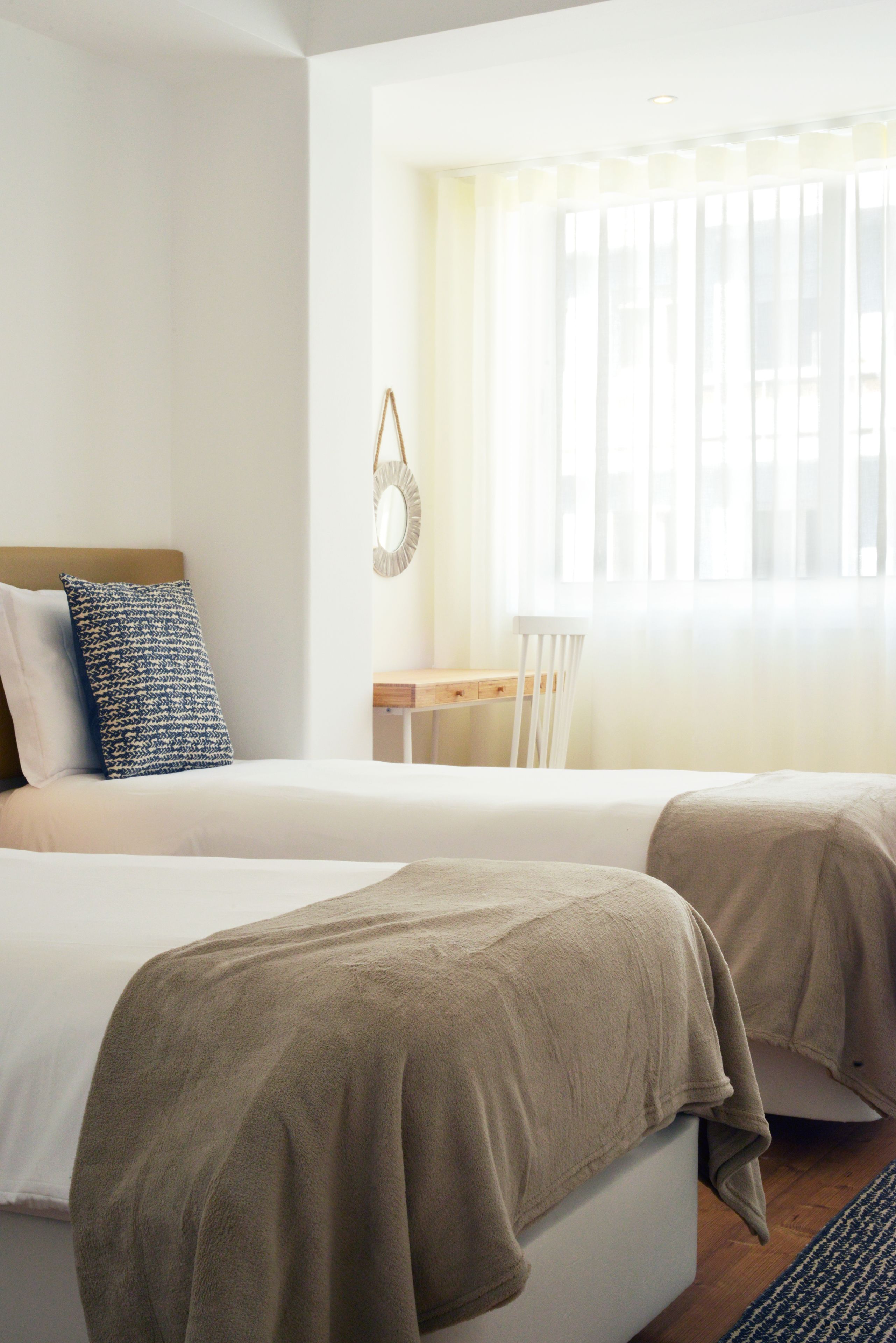 Hotellihuone, jossa on kaksi sänkyä, työpöytä ja tuoli.
