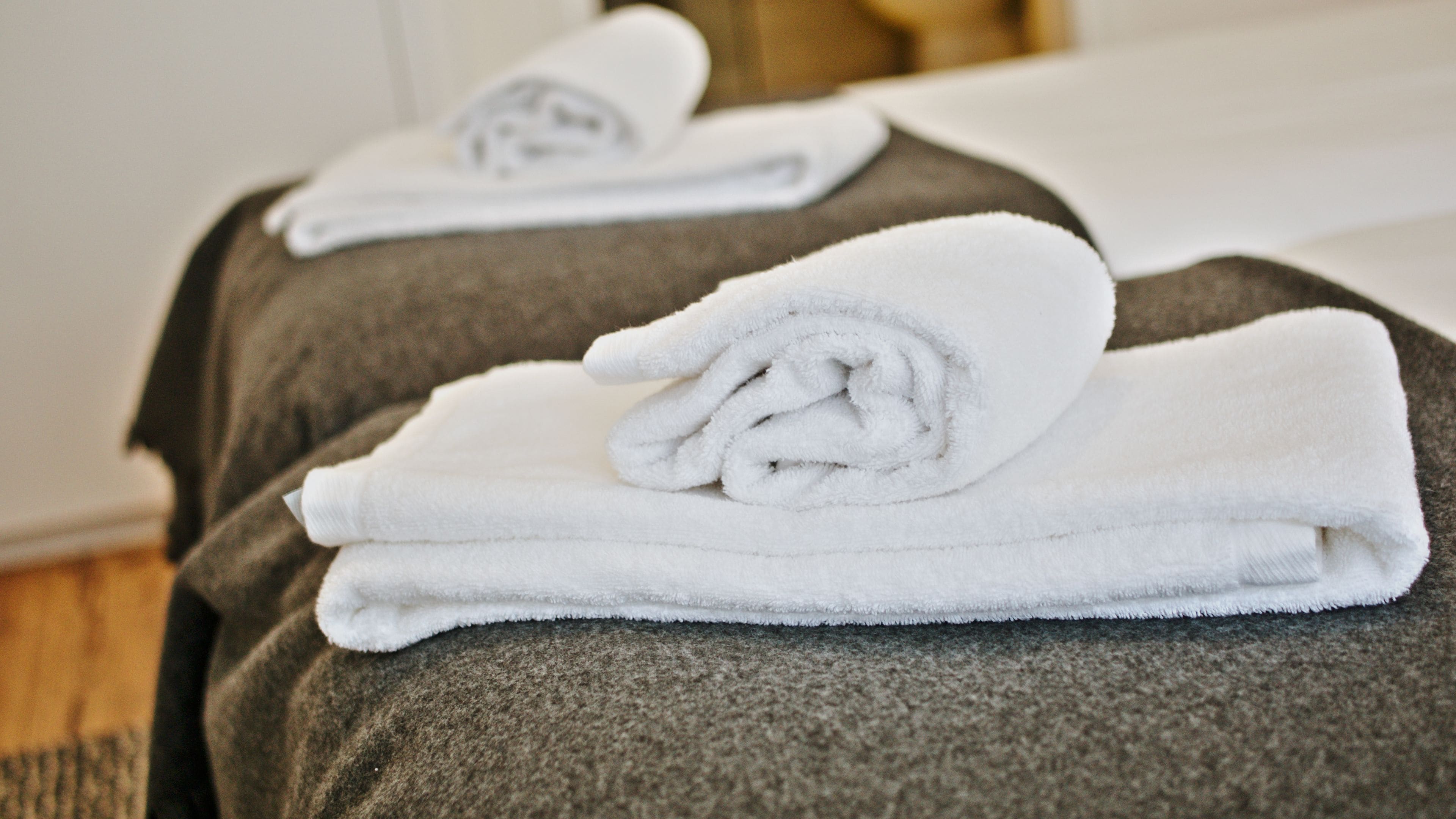 A neatly folded white towel on a dark gray pillow in a hotel room.
