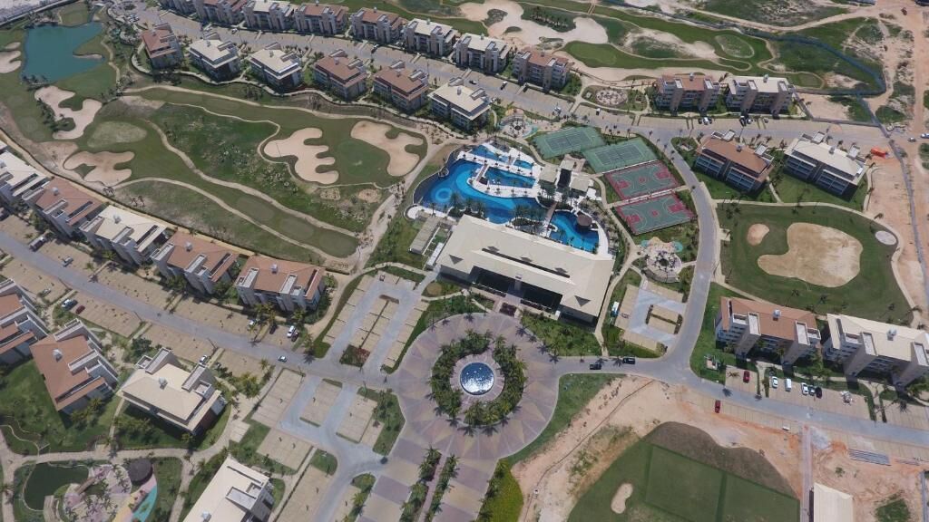 An aerial view of a resort with multiple buildings, a central pool area, and landscaped gardens.