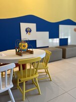 Una mesa redonda con mantel amarillo y blanco, rodeada de sillas amarillas.