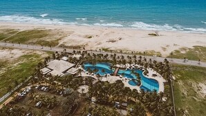 An aerial view of a resort with a large pool, beachfront, and a road leading to the property. - Golf Ville Resort By Brisa Do Golf (Aquiraz)