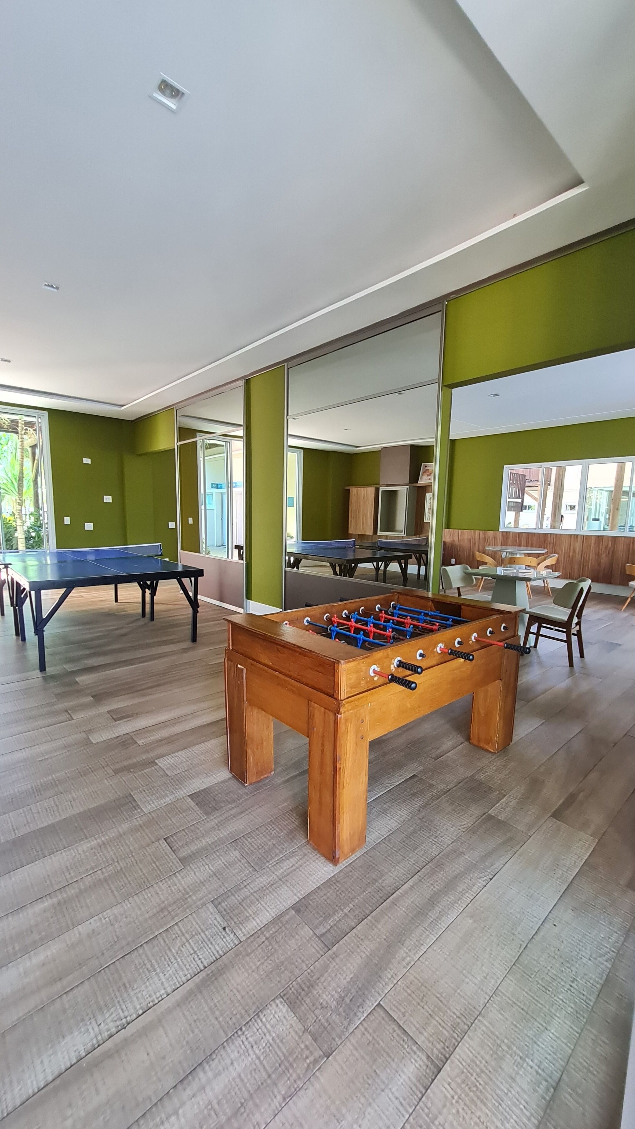 Amplo espaço interno com mesa de pebolim, mesa de pingue-pongue e mesa de bilhar.
