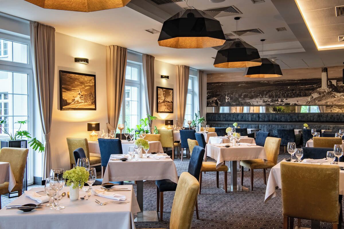 A restaurant with tables set for dining, large windows, and artwork on the walls.