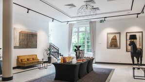 Un moderno vestíbulo de hotel con un mostrador de recepción negro, un sofá amarillo y una estación de café.