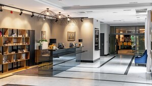 Un moderno vestíbulo de hotel con un mostrador de recepción, una zona de estar y un mostrador con una planta.