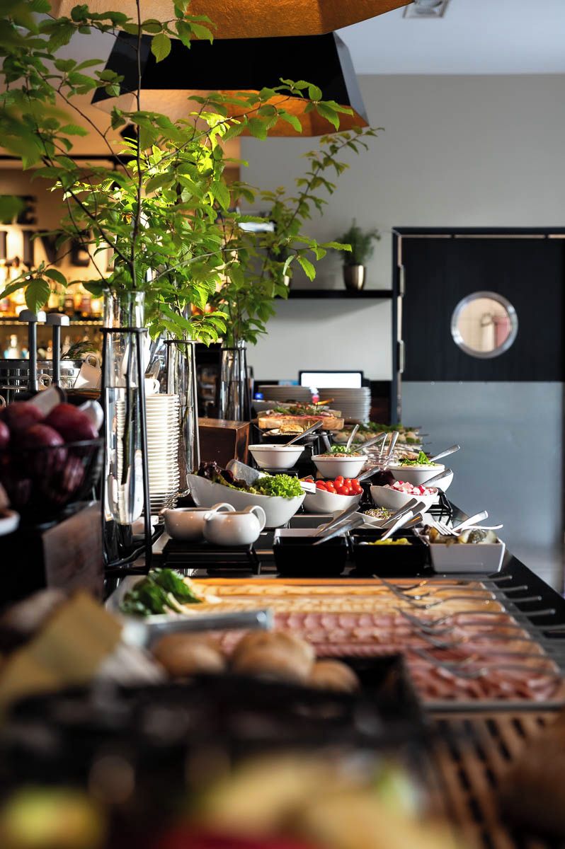 Ein reichhaltiges Buffet mit verschiedenen Speisen und Besteck, umgeben von Gläsern und Tellern.