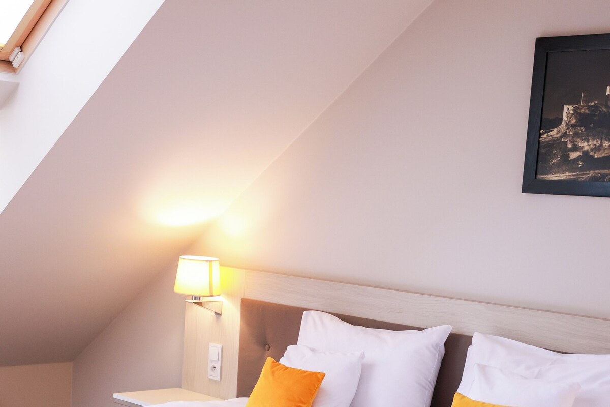 Una habitación de hotel con una cama, una mesita de noche, una lámpara y un cuadro en la pared.