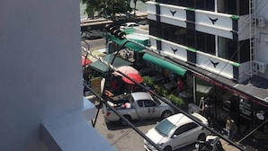 A multi-story building with balconies, a view of the sea, and parked cars below. - Seaview (Pattaya)