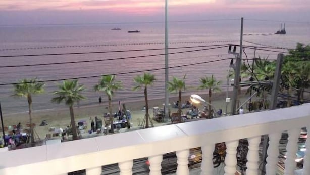 A beach view with palm trees and a few people. - Seaview (Pattaya)