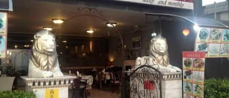 A restaurant named "ARMENIA" with a sign indicating it serves international food and seafood daily and monthly. There are two lion statues in front of the entrance.