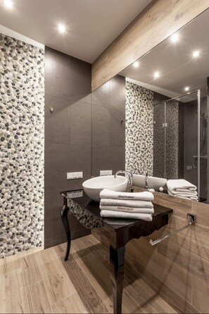 A modern bathroom with a large mirror, a wooden vanity, and a pebbled wall design.