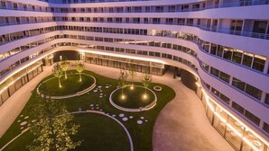 Ein modernes Mehrstöckhotel mit Innenhof, der bepflanzte Bereiche und runde Sitzgelegenheiten bietet.