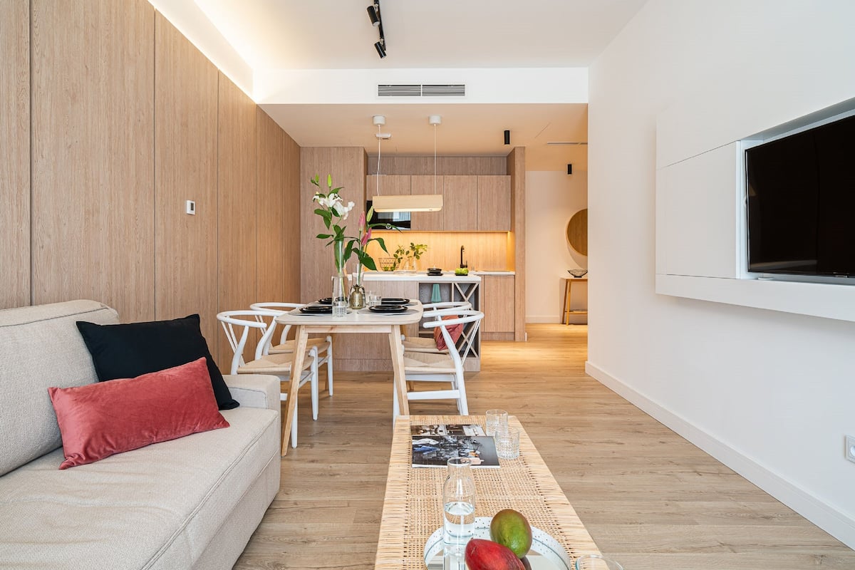 Un salon moderne avec un canapé, une table à manger et un coin cuisine à l’arrière-plan.