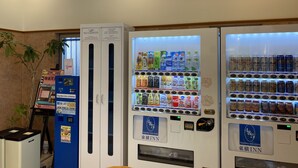 Un distributeur automatique proposant diverses boissons et en-cas, un distributeur de billets et un panneau indiquant l’emplacement d’un cinéma situé à proximité.