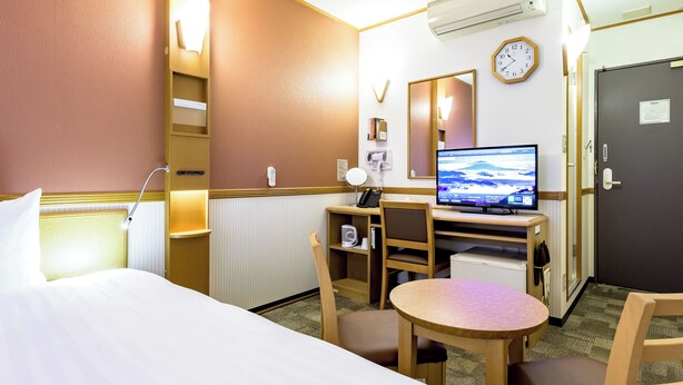 Une chambre d’hôtel équipée d’un lit, d’un bureau, d’une chaise et d’un téléviseur.