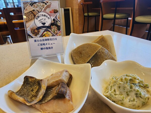 A menu board with local food options and two dishes: grilled fish and a creamy vegetable dish.