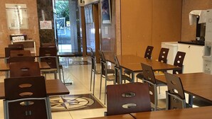 A dining area with tables and chairs, a water dispenser, and a view of the outside. - Toyoko Inn Hiroshima-eki Minami-guchi Migi (Hiroshima)
