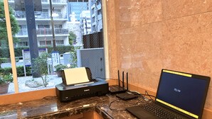Un espace de travail équipé d’un ordinateur portable, d’une imprimante et de plusieurs câbles Ethernet, le tout posé sur un comptoir en marbre.