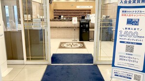 L’entrée d’un hôtel, avec un comptoir de réception, un tapis bleu et un panneau publicitaire annonçant un coupon Internet d’une valeur de 1 500 yens.