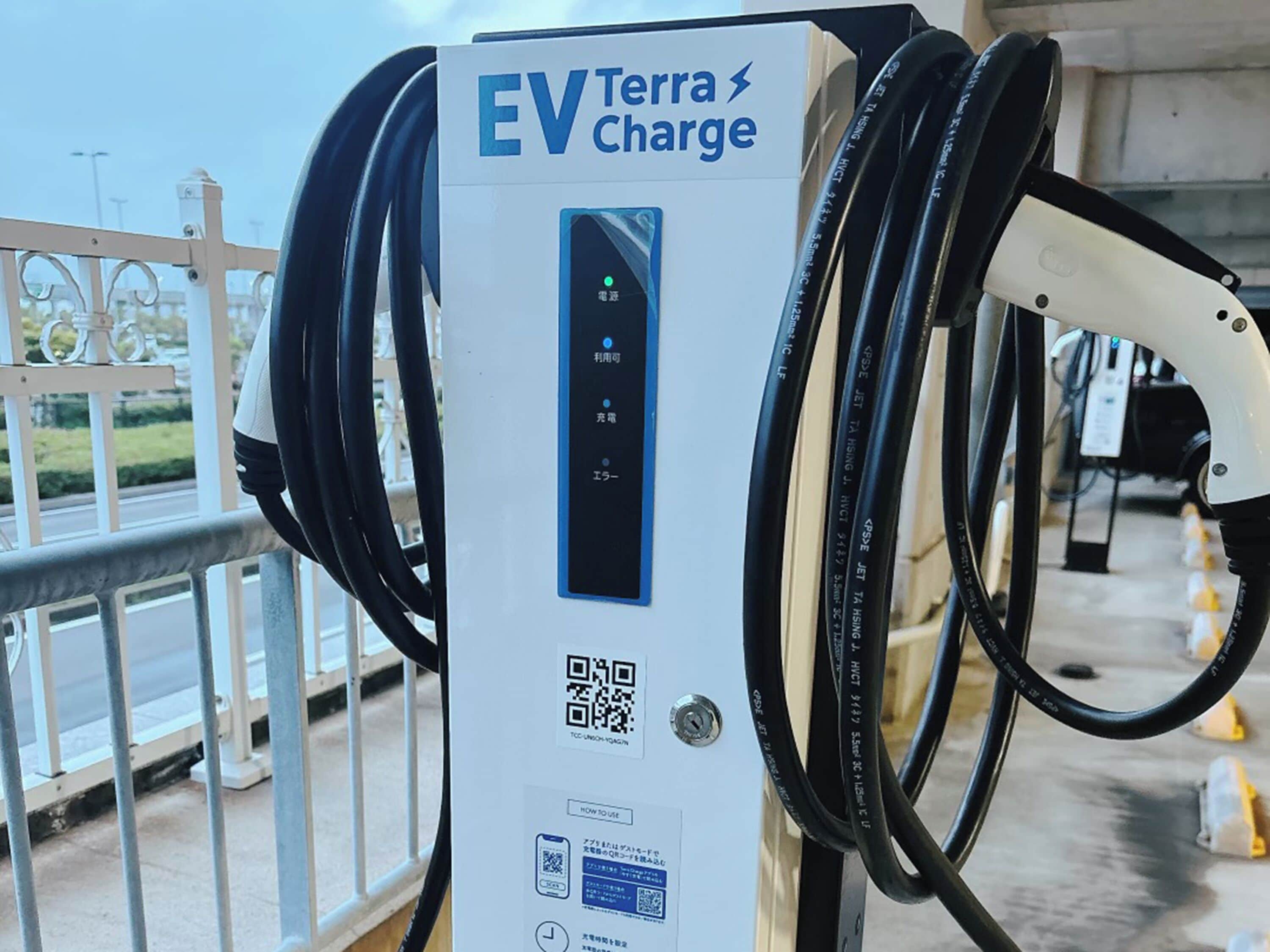 Una estación Terra Charge para vehículos eléctricos con múltiples cables de carga, una pantalla digital y códigos QR con instrucciones.
