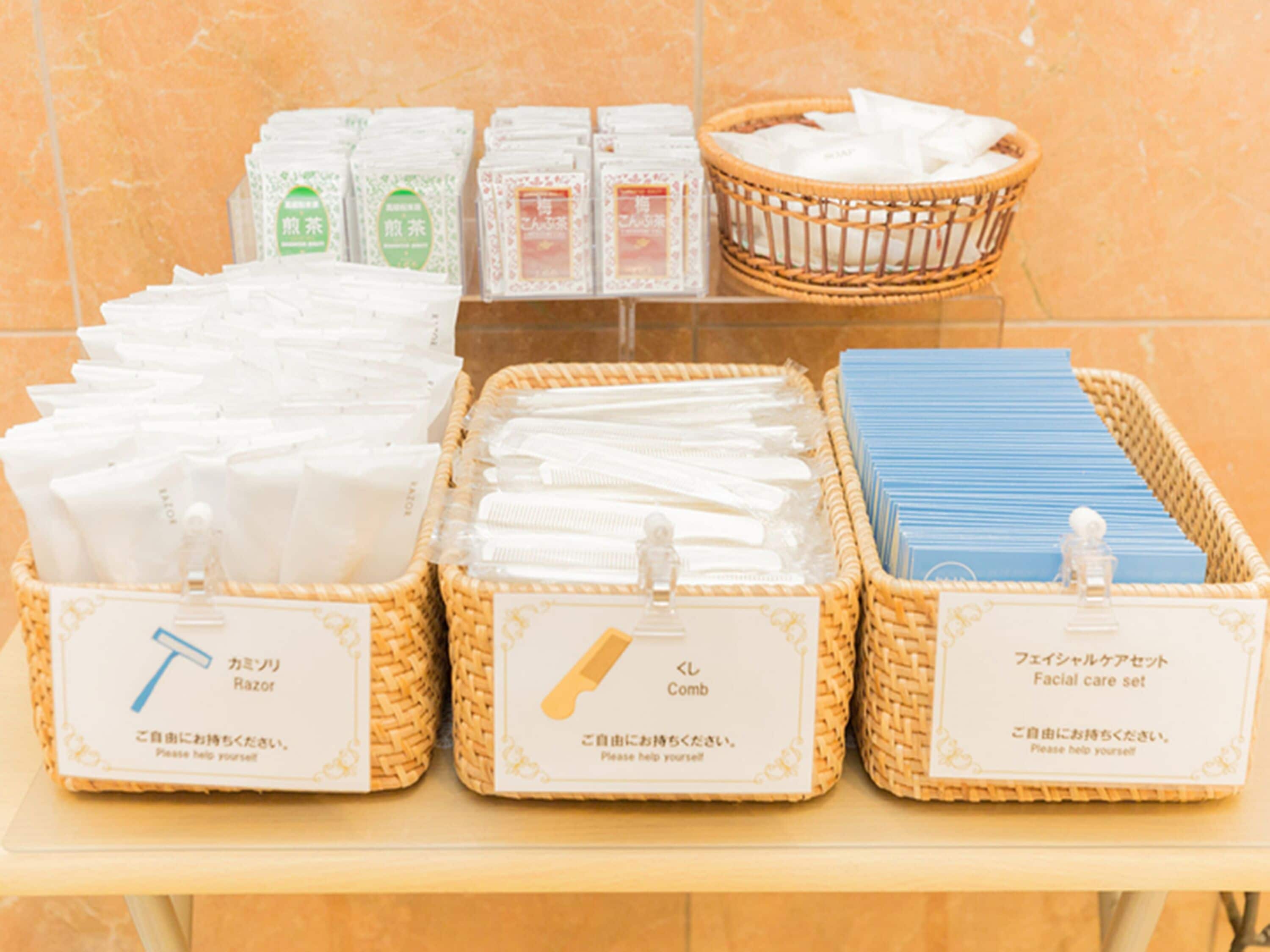 Une sélection de produits d’hygiène personnelle, comprenant des rasoirs, des peignes et un ensemble de produits pour les soins du visage, disposés dans des paniers en osier sur une étagère.