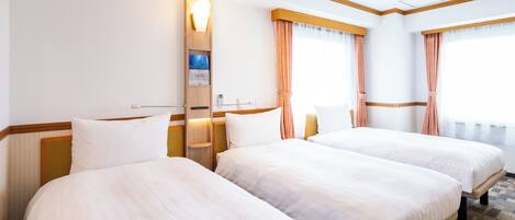 Habitación de hotel con dos camas, cabecero de madera, mesita de noche, lámpara de pared y ventana con cortinas.