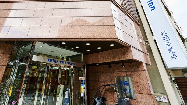 Ein Hotel Eingang mit einem Schild mit der Aufschrift 'Toyoko Inn' und einem weiteren Schild in einer Fremdsprache.