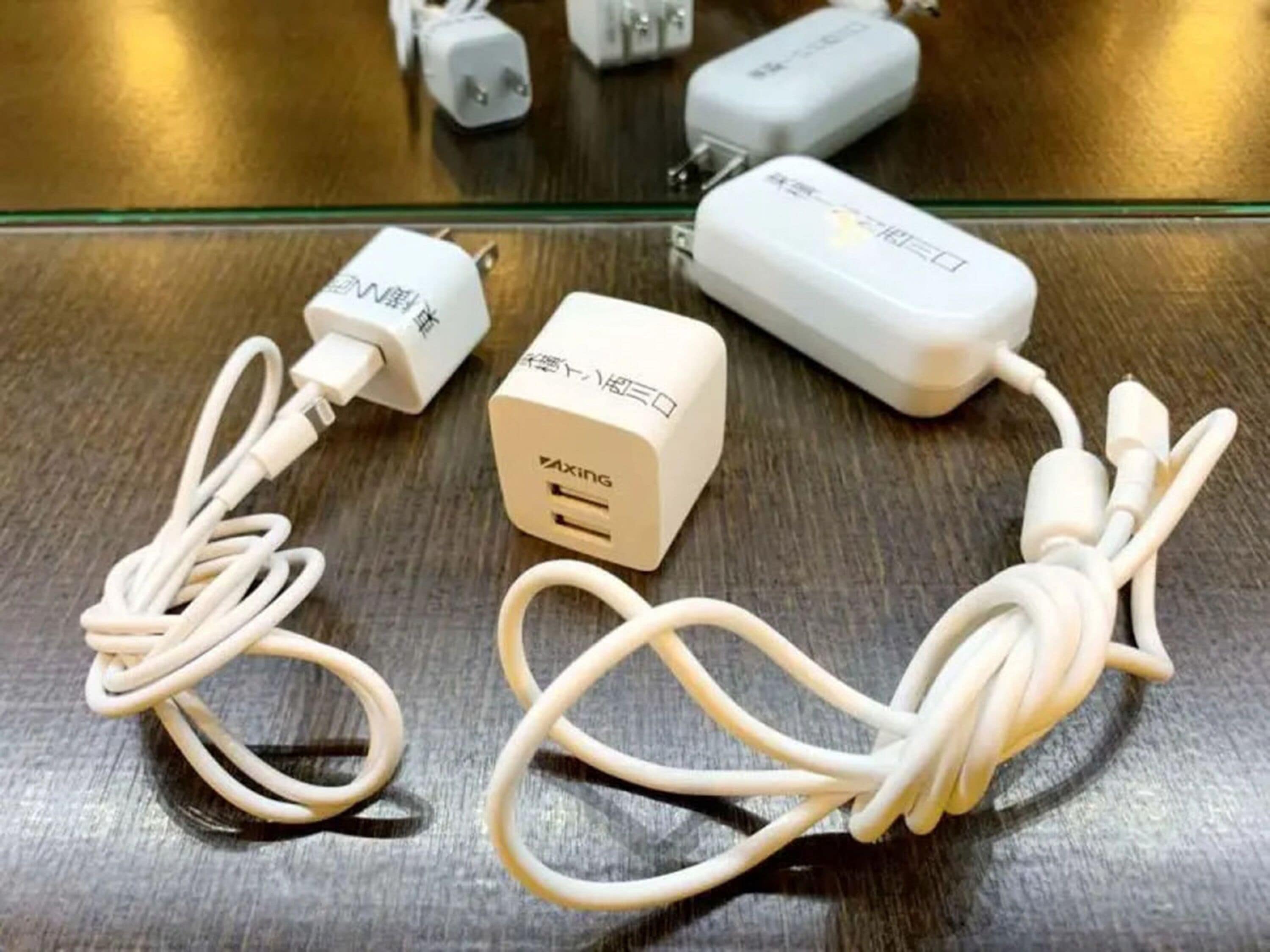 Three power adapters with cables on a reflective surface.