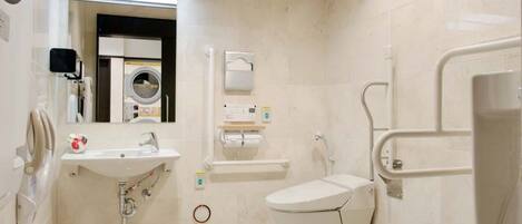 A modern bathroom with a sink, toilet, and handrail.
