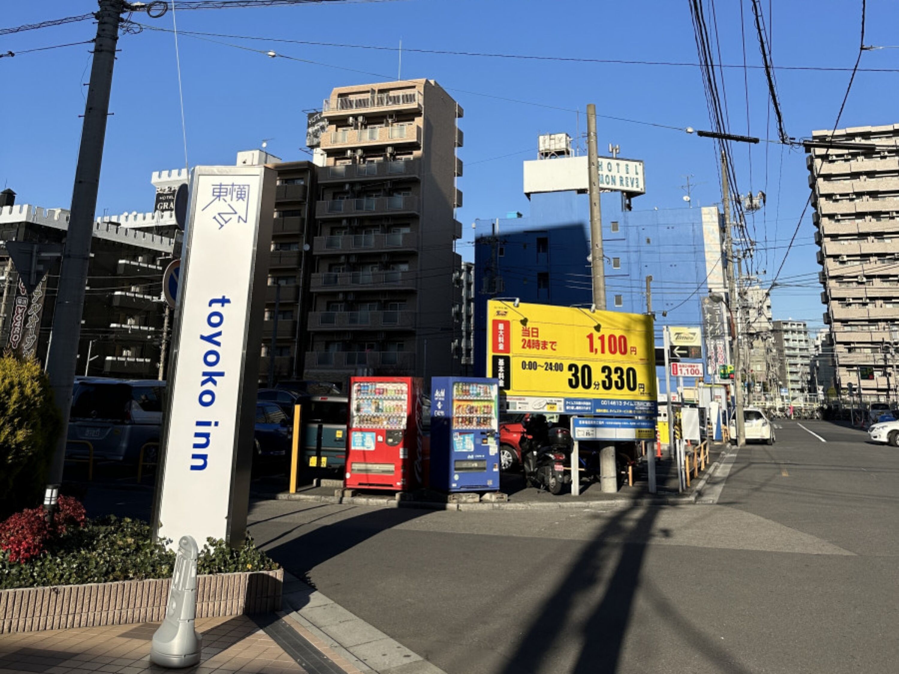 Une vue de rue avec une enseigne indiquant « Toyoko Inn » et une publicité jaune pour un hôtel.