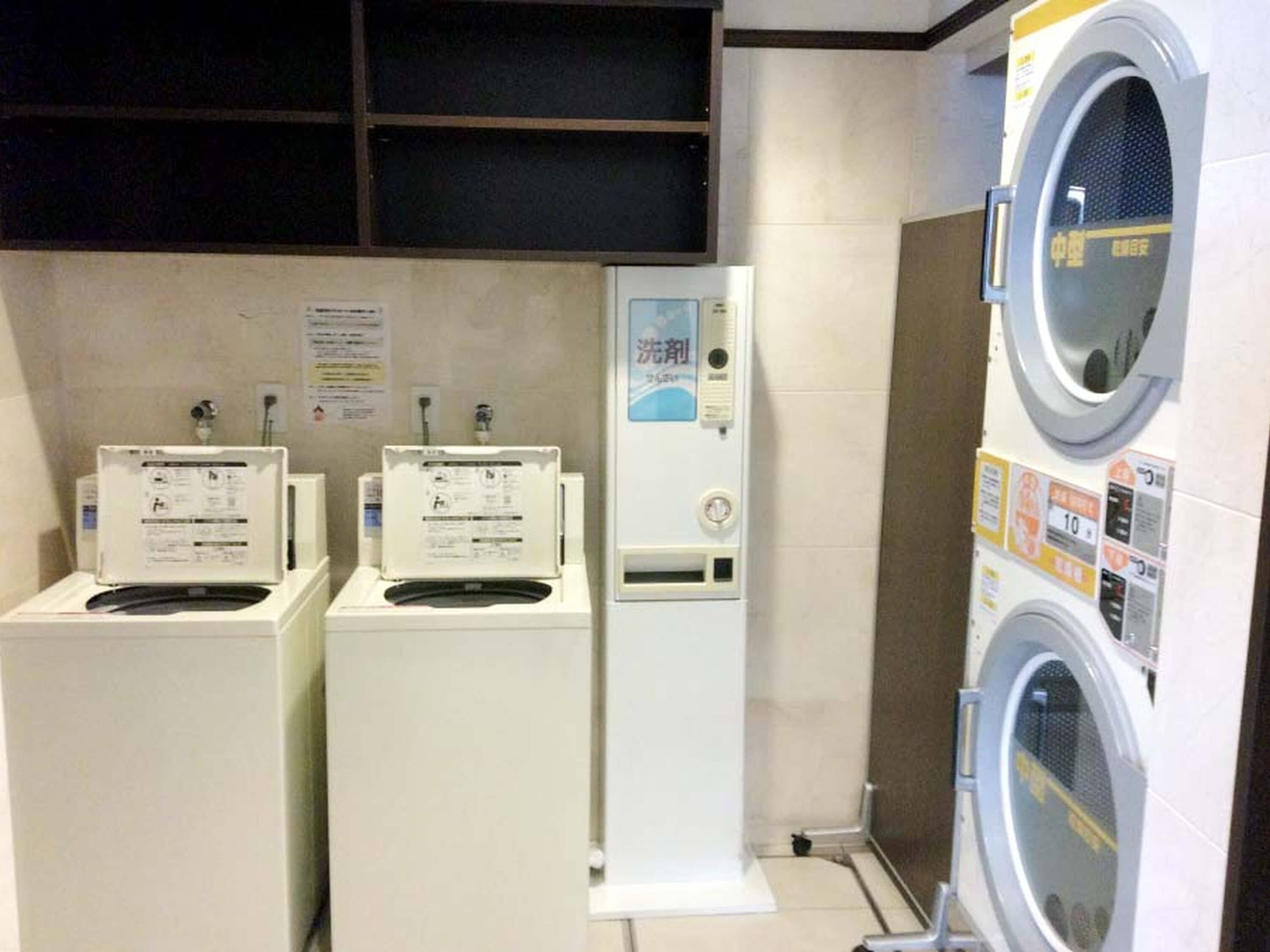 A laundry facility with three washing machines and a dryer, each with control panels and instructions.